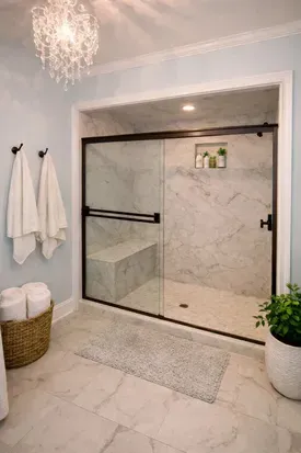 Spacious walk-in tiled shower with a built-in bench for comfortable seating. The bathroom features a wide entry door. The bathroom door is wide enough for a wheelchair but the shower is NOT ADA compliant. There are no rails and there is a step. 