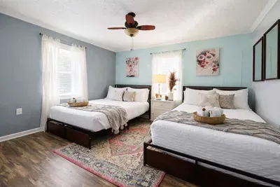 This bedroom features two full-size beds, each with two built-in drawers underneath for extra storage. The headboards include a convenient shelf and an integrated charging station for guests.
