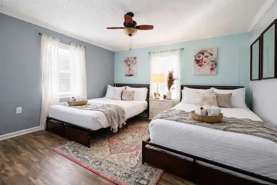 This bedroom features two full-size beds, each with two built-in drawers underneath for extra storage. The headboards include a convenient shelf and an integrated charging station for guests.