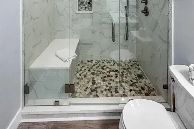 A clean walk in shower with modern tile and a built in bench, perfect for rinsing off and relaxing.