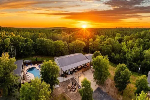 Aerial View of Secluded Wooded Retreat with Pool and Outdoor Entertainment at Sunset