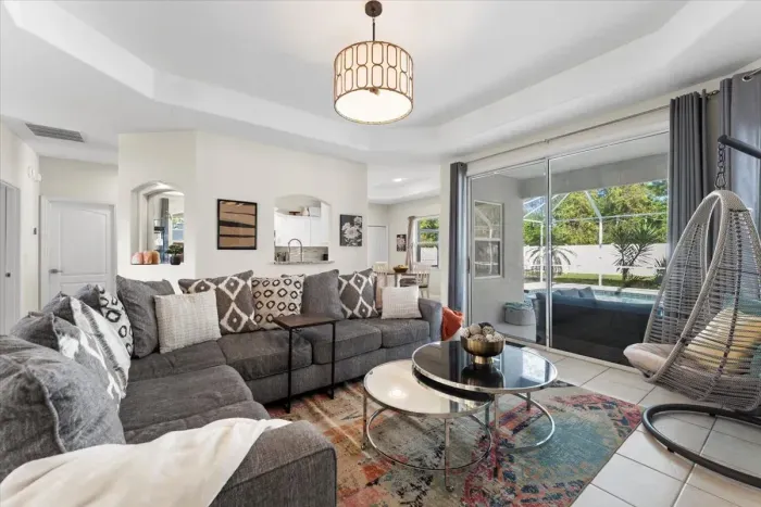 Welcome home, enjoy the large sectional couch and hanging chair with a great view of the pool.