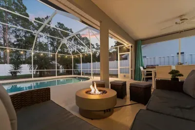 Outdoor lounge area with fire pit and screened pool views, ideal for unwinding after a day at the beach.