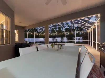 Outdoor dining area inside the screened enclosure, perfect for meals by the pool in a breezy setting.
