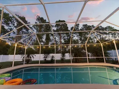 Screened in pool enclosure with string lights creating a relaxing space for evening swims and outdoor lounging.