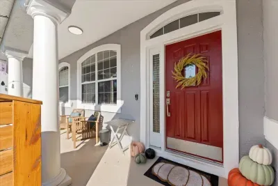 Covered front porch with seating and a bright entry door that sets the tone for a relaxing stay.