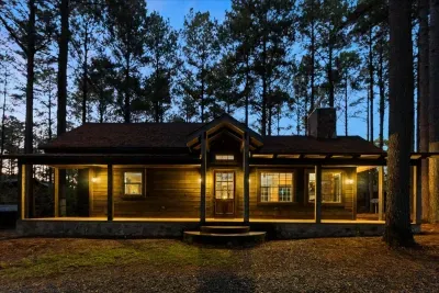 Charming cabin exterior glowing warmly at dusk, surrounded by peaceful pines.