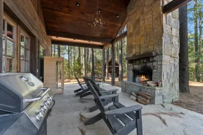 Covered outdoor lounge with fireplace and forest views, ideal for relaxing evenings.