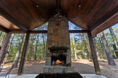 Covered outdoor fireplace area offering warmth and comfort surrounded by tall pines.