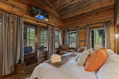 Spacious bedroom with rustic wood walls and a cozy reading nook by the window.