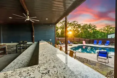 This covered outdoor kitchen and bar makes evenings easy, whether you are cooking, gathering, or enjoying the view of the pool
