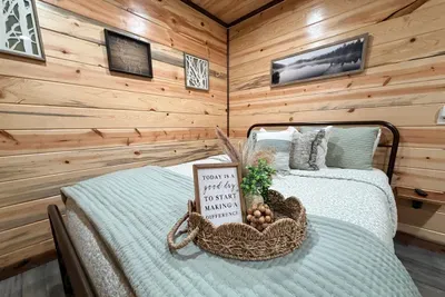 A cozy bedroom tucked into the cabin with warm wood walls and a comfortable bed that makes it easy to unwind