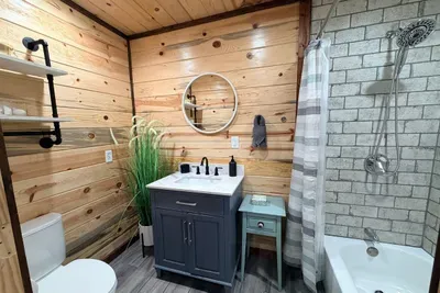 A charming bathroom with rustic wood walls, a walk in shower, and everything you need to refresh comfortably