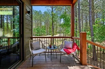 Covered balcony with lounge chairs and peaceful forest views off the second primary bedroom
