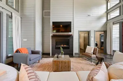 Bright living room with fireplace, mounted TV, and tall windows by the entry