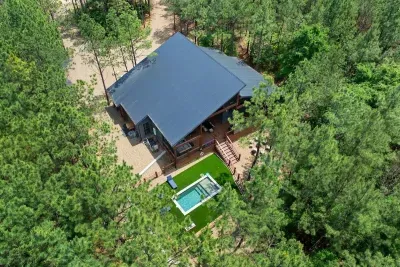 Aerial view of cabin surrounded by tall pines