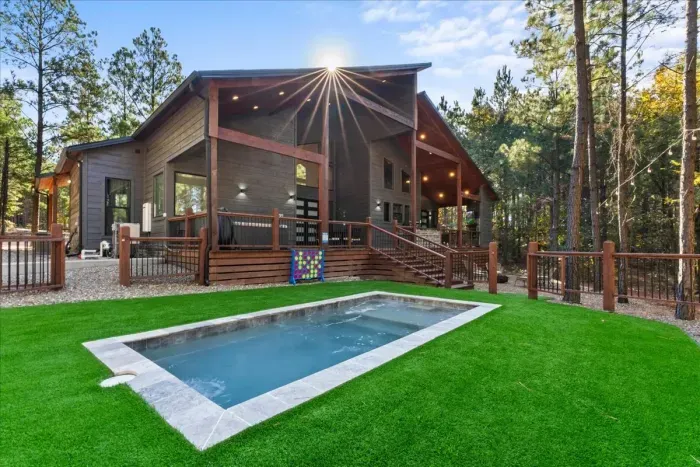 A modern cabin retreat with a splash of fun-relax on the spacious deck, lounge poolside, or take a dip in your private pool. Surrounded by towering pines, this outdoor oasis blends cozy cabin living with resort-style comfort.