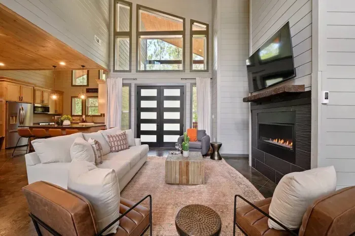Bright living room with fireplace, mounted TV, and tall windows by the entry