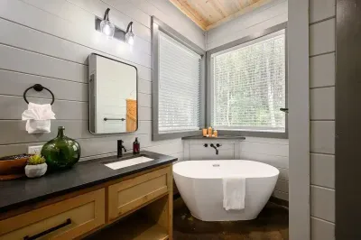 Bathroom with soaking tub, double vanity, and forest view window