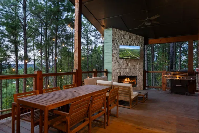 Covered outdoor dining and lounge area featuring a cozy fireplace—perfect for alfresco meals.