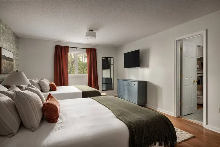 This spacious double-queen room features a full dresser, a 50” Roku TV, and calming woodland views.