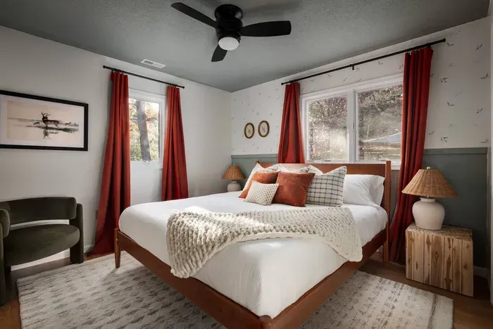 Step into a serene retreat featuring a plush king bed, whimsical bird-patterned wallpaper, a cozy lounge chair, and a 50” Roku TV for effortless relaxation.