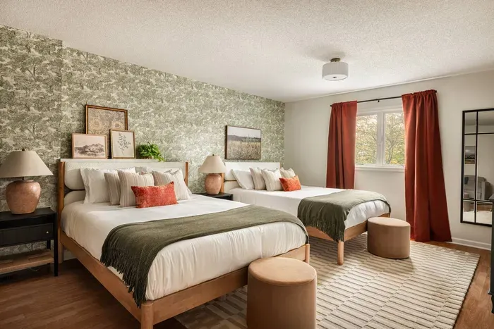 A spacious retreat with two plush queen beds, warm earthy tones, and serene nature-inspired wallpaper—perfect for families or groups.