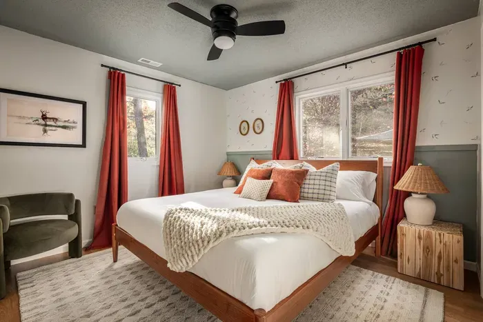 Step into a serene retreat featuring a plush king bed, whimsical bird-patterned wallpaper, a cozy lounge chair, and a 50” Roku TV for effortless relaxation.
