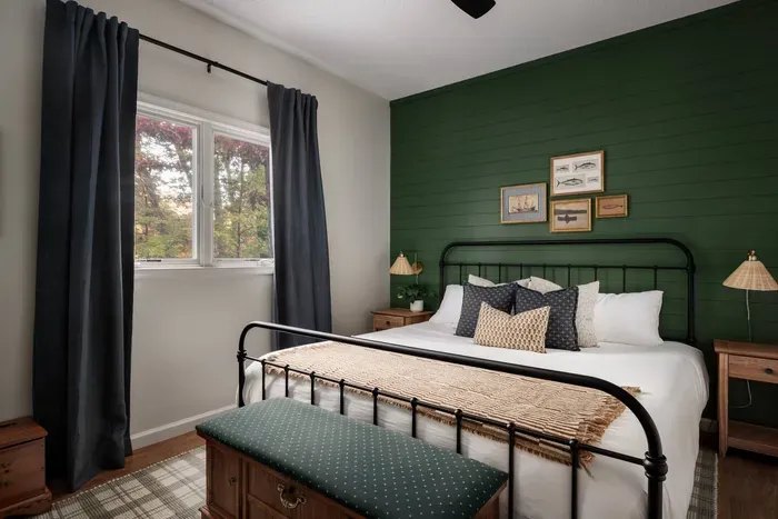 Get comfy in this king bedroom featuring a bold green accent wall, vintage fish-and-boat artwork, an antique cedar chest bench, and a 50” Roku TV for easy streaming.