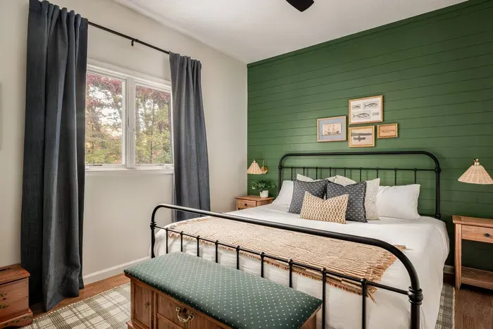 Get comfy in this king bedroom featuring a bold green accent wall, vintage fish-and-boat artwork, an antique cedar chest bench, and a 50” Roku TV for easy streaming.