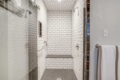 Modern, ADA-compliant walk-in shower with a built-in bench and stylish tile work
