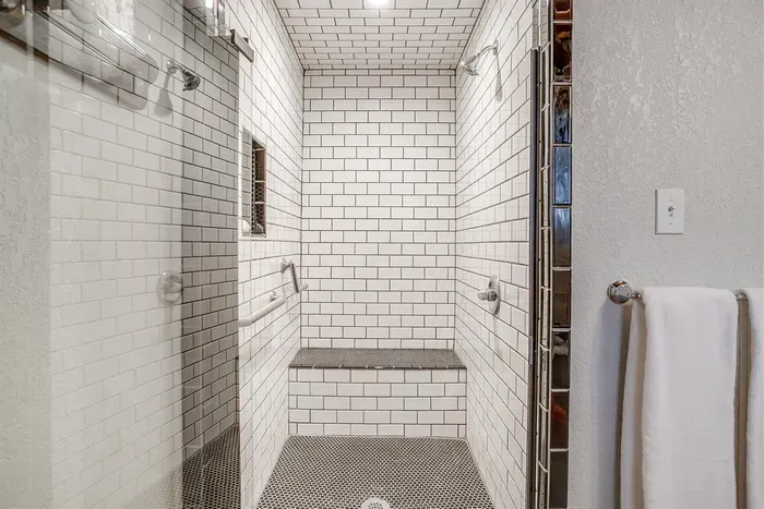 Modern, ADA-compliant walk-in shower with a built-in bench and stylish tile work