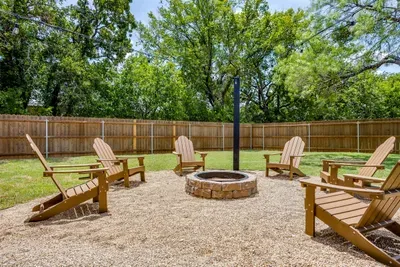 Stone fire pit ringed with six Adirondack chairs on pea gravel.