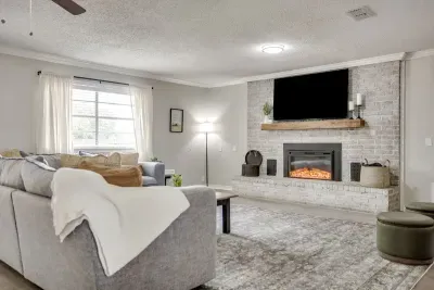 Whitewashed brick fireplace with a wood mantel and a big smart TV above it.