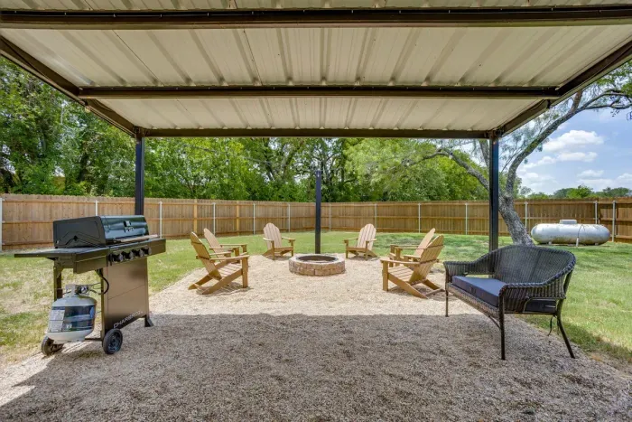 Covered pavilion with a gas grill and propane provided, opening right onto the fire pit.