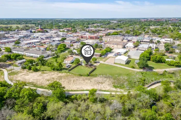 Wide aerial showing The Hive's backyard backing directly up to the Bosque River Trail — green, peaceful, and steps from nature.