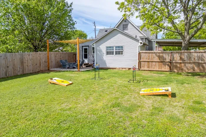 Fully fenced backyard with cornhole, open lawn, and plenty of room for pets, kids, and group activities.