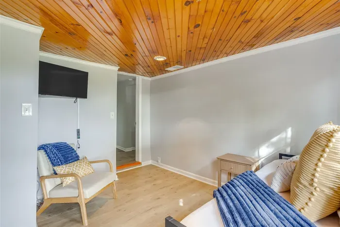 Third bedroom with twin beds, wood ceiling, Smart TV, and a cozy reading chair — comfortable, private, and full of character.