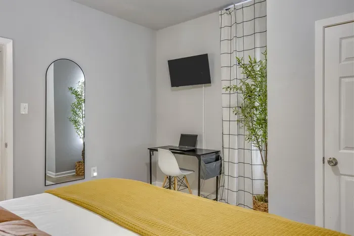 Master bedroom with full length mirror, workstation, Smart TV, and arched doorway detail — private, functional, and full of character.