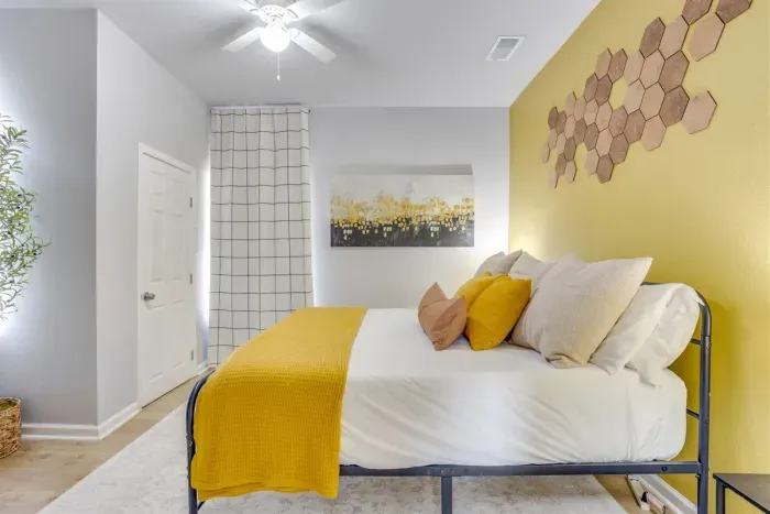 King master bedroom with yellow bedding, honeycomb wall art, and sunflower canvas — warm, bright, and built around The Hive's signature bee theme.