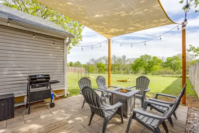 Covered back patio with sail shade, string lights, gas grill, Adirondack seating, and a fire pit — your own private outdoor hangout.
