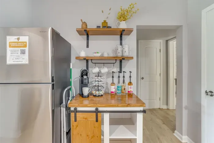 Full coffee bar setup with K-cup maker, mugs, syrups, and open wood shelving — your morning routine sorted from day one.