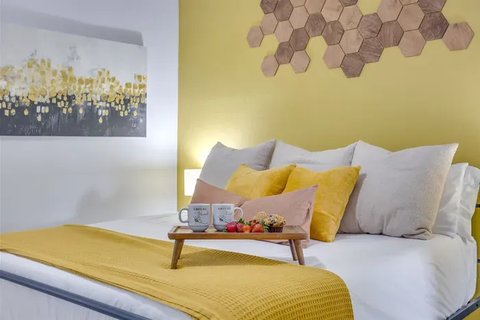 King master bedroom with yellow bedding, honeycomb wall art, and a breakfast tray — start your morning in style at The Hive.