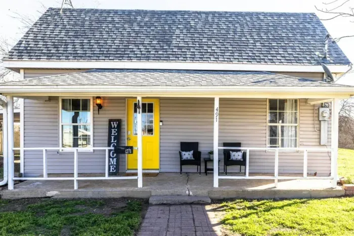 The bright and welcoming front porch invites you in with its vibrant yellow door, creating a cheerful first impression.
