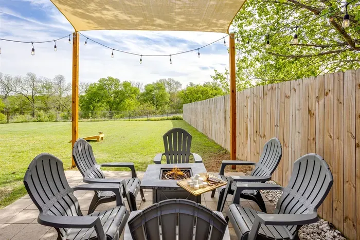 Sail shade patio with string lights, fire pit, and Adirondack chairs — the perfect spot for evening gatherings under the Texas sky.