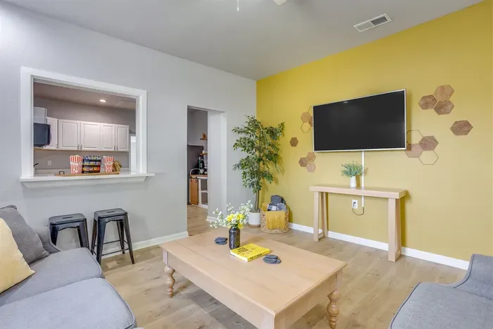 Living and dining area with Smart TV, yellow accent wall, kitchen bar seating, and an open layout perfect for groups.