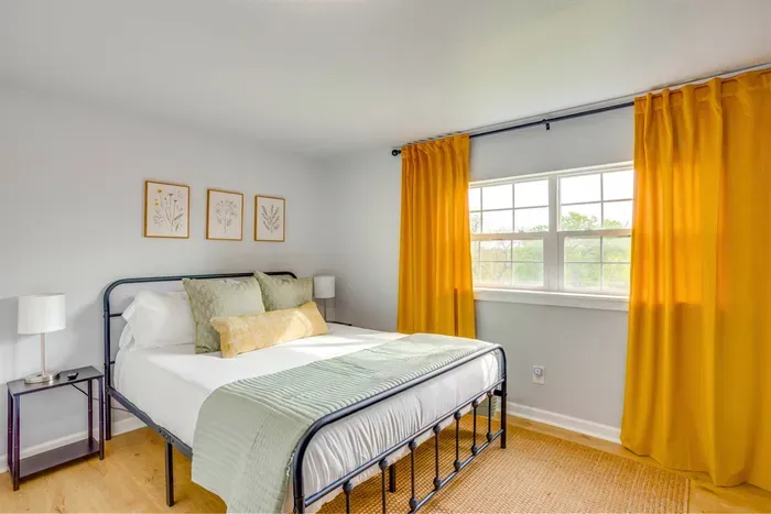 Bright guest bedroom with queen bed, iron bed frame, and golden curtains — comfortable and stylish for every guest.