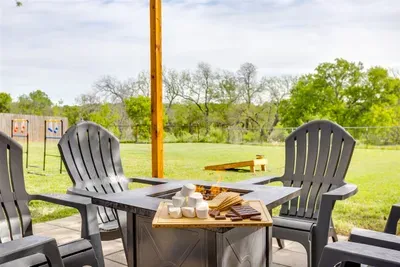 Back patio with Adirondack seating, fire pit, and wide open backyard views — the perfect spot to unwind after a day out in Stephenville.