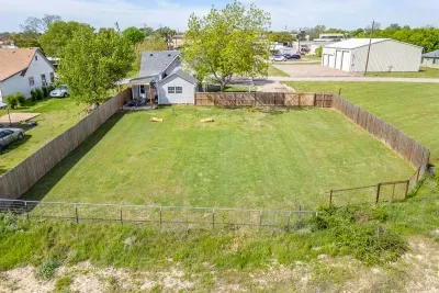 Top-down aerial showing the full fenced backyard, covered patio, and open green space — one of the biggest yards you'll find this close to downtown.