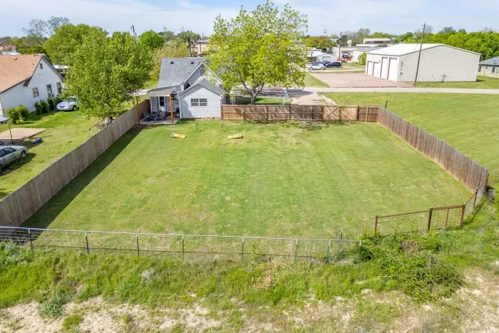 Top-down aerial showing the full fenced backyard, covered patio, and open green space — one of the biggest yards you'll find this close to downtown.